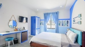 Une chambre à coucher avec un lit, un bureau, une chaise, un téléviseur et une fenêtre avec des rideaux.