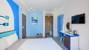 Une chambre d’hôtel avec un lit, un bureau doté d’un miroir, une télévision et une salle de bain visible à travers une porte ouverte.