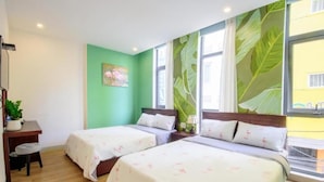 Une chambre d’hôtel avec deux lits, un bureau, une chaise et une plante en pot.
