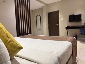 A hotel room with a bed, a desk, a chair, a television, and a door. - Surendra Landmark By Spree Hotels (Bhopal)