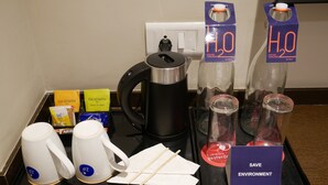 A hotel room's breakfast tray with tea bags, a coffee maker, a water bottle, and a 'SAVE ENVIRONMENT' sign. - Surendra Landmark By Spree Hotels (Bhopal)