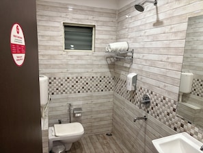 A bathroom with a toilet, sink, and shower. There is a hand dryer and a towel rack. - Surendra Landmark By Spree Hotels (Bhopal)