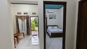 Una habitación con cama, un banco y una puerta que da a un balcón.