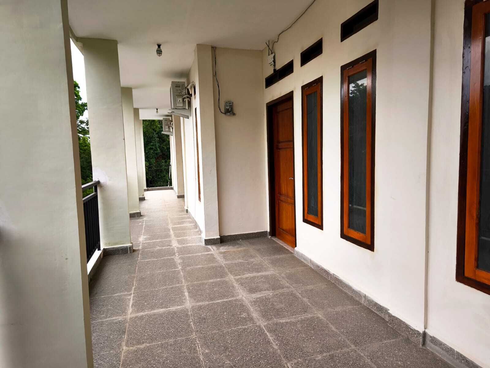 A corridor with tiled flooring, white walls, and wooden doors.