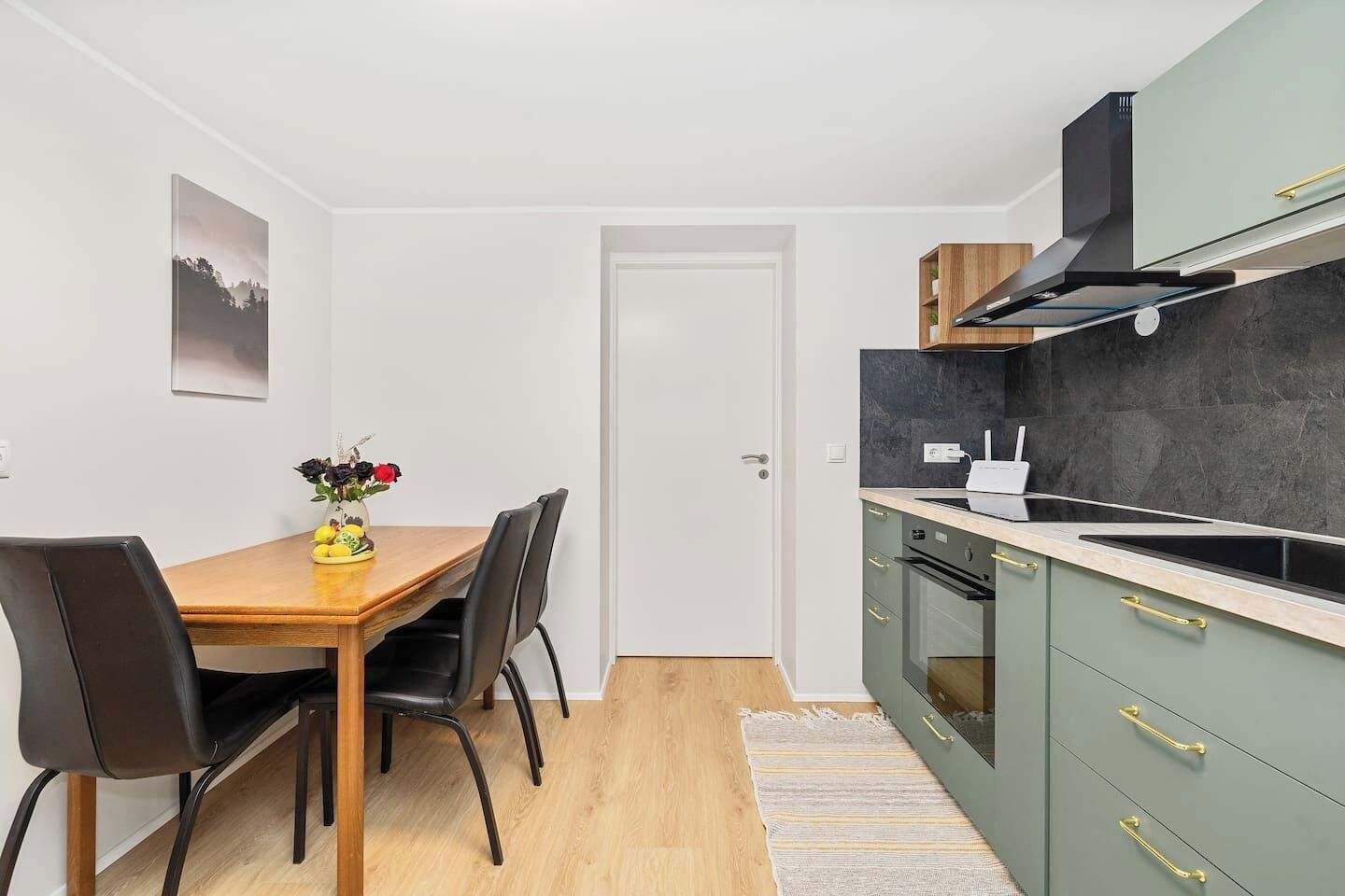 A compact kitchen with a dining table, chairs, a stove, and a microwave.