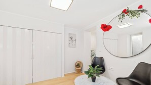 Una sala de estar moderna con una mesa de centro redonda de mármol, un sillón negro, una silla de mimbre y un espejo grande en la pared.