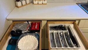 Una cocina con un cajón que contiene utensilios de cocina y una bolsa de plástico.