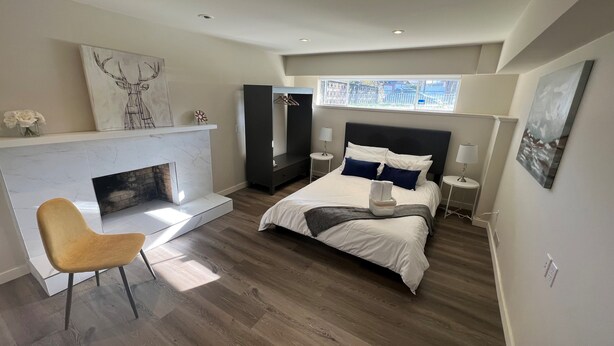 Un dormitorio moderno con una cama grande, una chimenea, un rincón de descanso y vistas al exterior.
