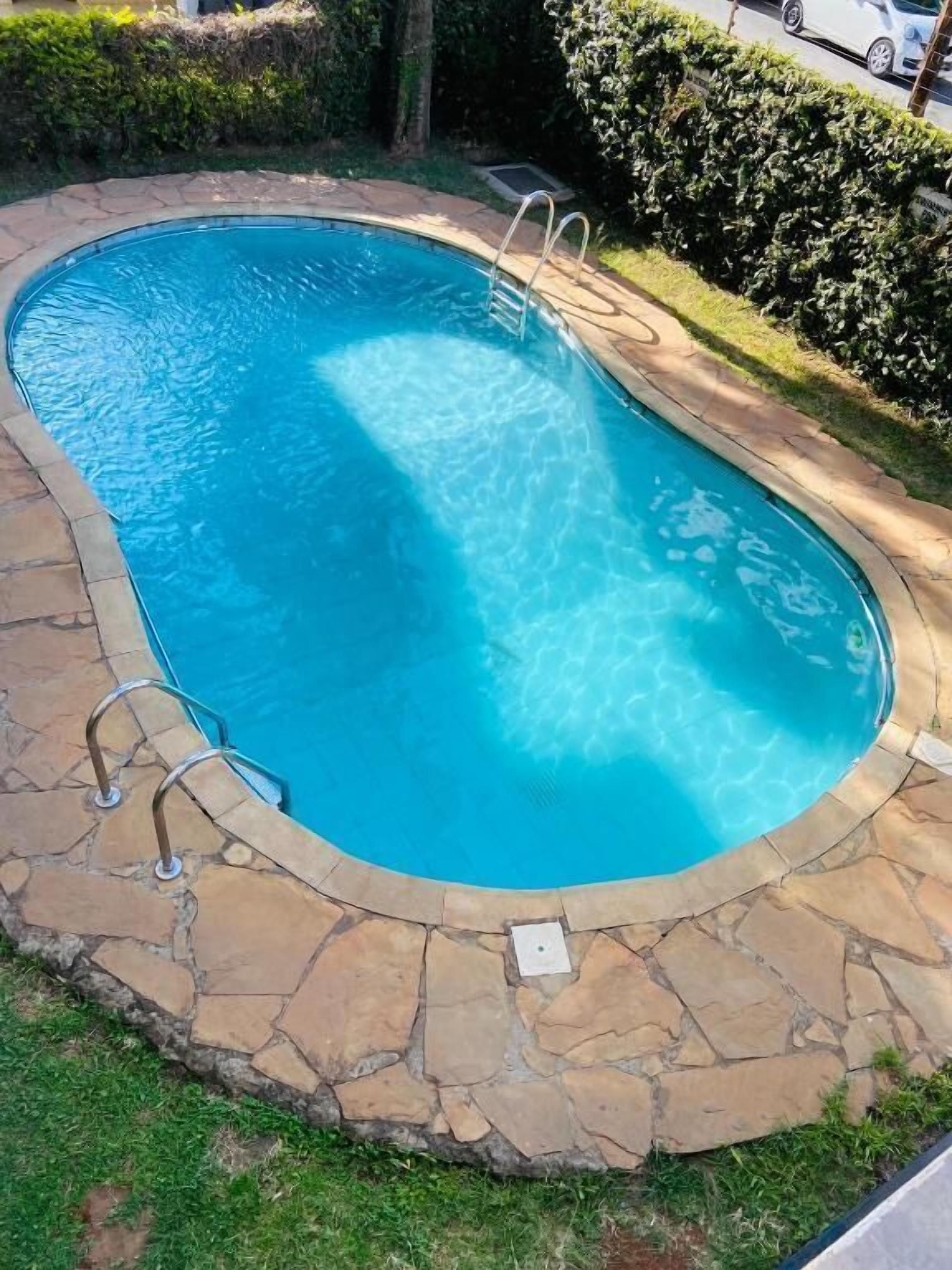 A swimming pool with a stone border and metal handrails.
