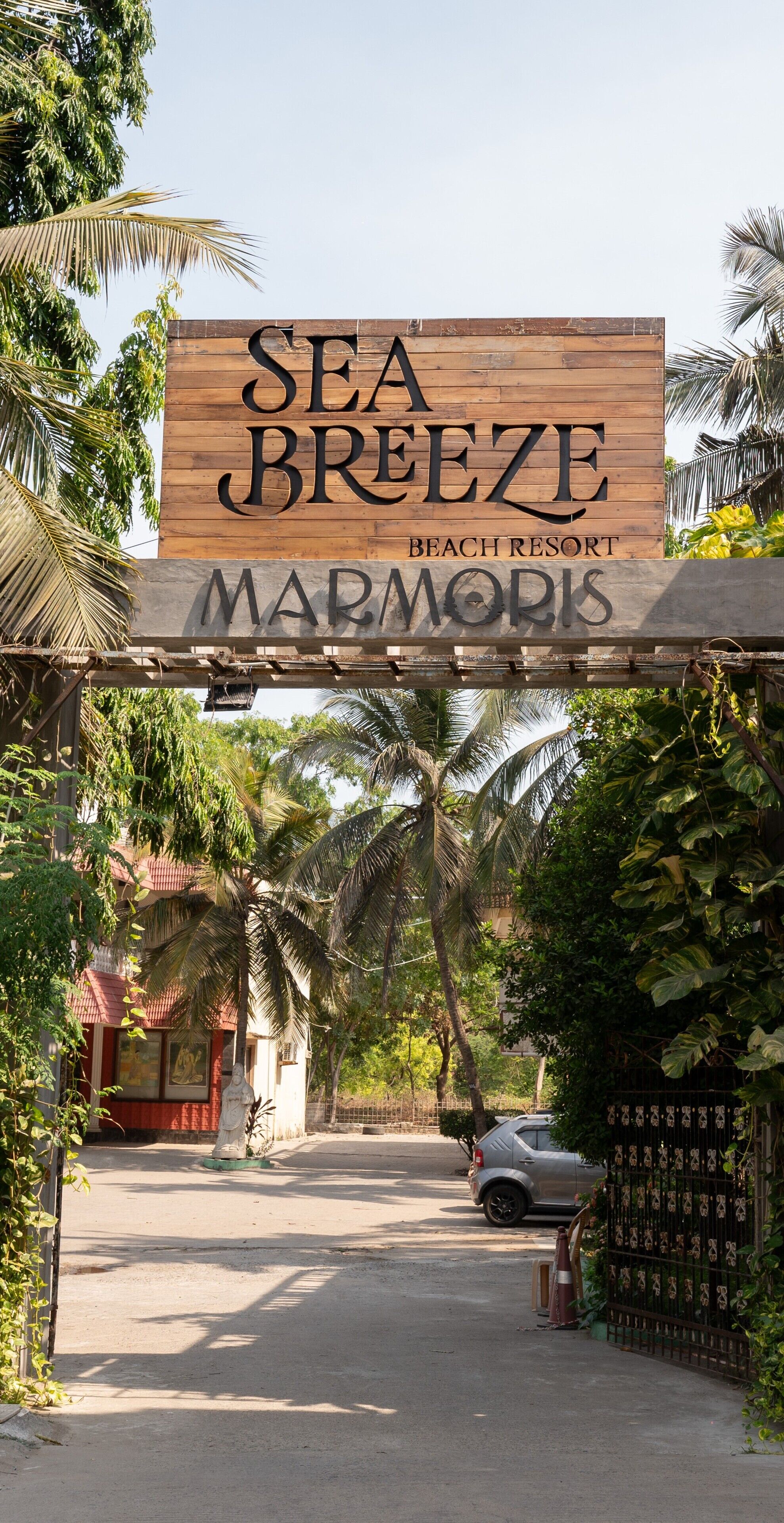 Un letrero de madera para el Sea Breeze Beach Resort, con el nombre 'Marmoris' debajo.