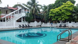 A swimming pool with lounge chairs and a white fence. - Sea Breeze Beach Resort (Mahabalipuram)