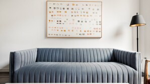 Ein modernes Wohnzimmer mit einem blauen Sofa, einem gerahmten abstrakten Kunstwerk und einer Stehlampe.