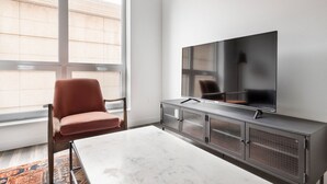 Ein modernes Wohnzimmer mit einem großen Flachbildfernseher an der Wand, einem bequemen Sessel und einem Marmortisch.