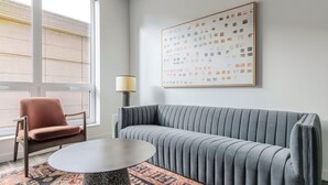 Ein modernes Wohnzimmer mit einem grauen Sofa, einem runden Tisch, einem gemusterten Teppich, einer Lampe und einem Sessel.