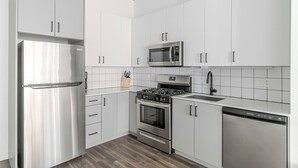 Eine moderne Küche mit weißen Schränken, Edelstahlgeräten und Holzboden.