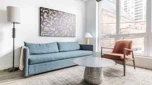 A modern living room with a sofa, a chair, a coffee table, and a large window with a view of buildings. - Blueground | Near North Side, rooftop, nr Riverwalk (Chicago)