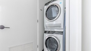 A laundry room with two stacked front-loading washing machines and a door with a handle. - Blueground | Near North Side, rooftop, nr Riverwalk (Chicago)