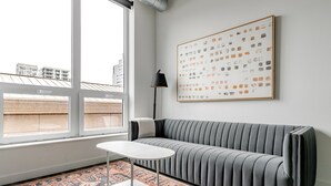 Ein modernes Wohnzimmer mit einem grauen Sofa, einem weißen Couchtisch und einem gemusterten Teppich.