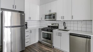 Eine moderne Küche mit Edelstahlgeräten, weißen Schränken und einer gefliesten Rückwand.