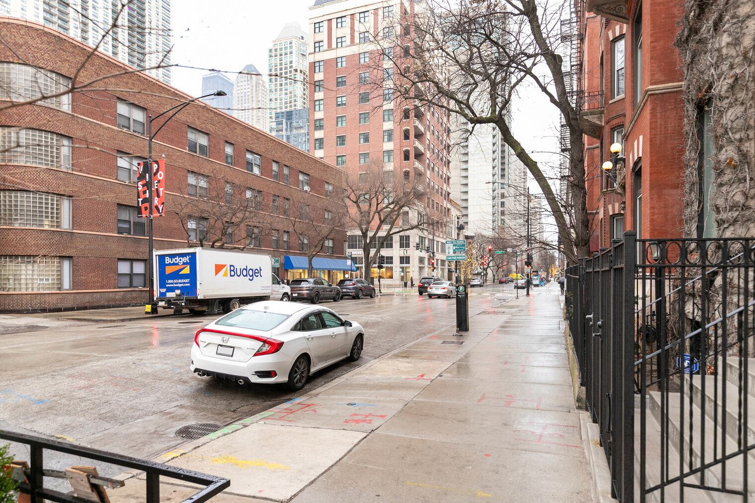 A city street with a white car and a Budget delivery truck.