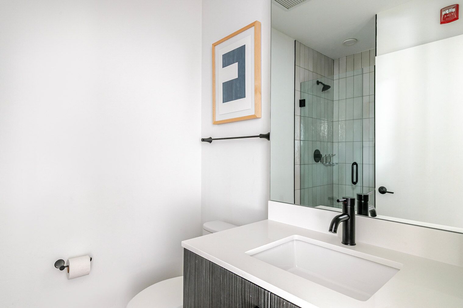 A modern bathroom with a white sink, a large mirror, and a glass shower enclosure.