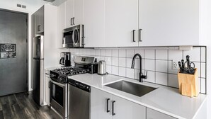 A modern kitchen with stainless steel appliances, white cabinetry, and a black faucet. - Blueground | Near North Side, rooftop, nr Chicago River (Chicago)