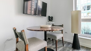 A modern dining area with a round table, two chairs, a bowl, a flat-screen TV, and a lamp. - Blueground | Near North Side, rooftop, nr Chicago River (Chicago)