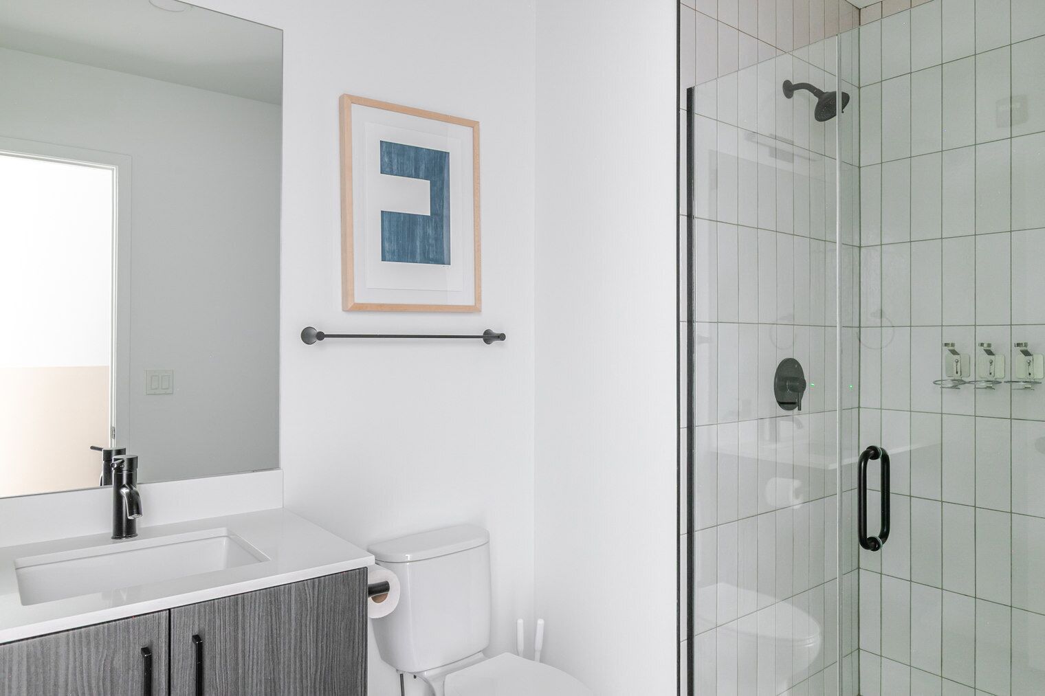 Een moderne badkamer met een douchecabine van glas, een witte wastafel en een toilet.