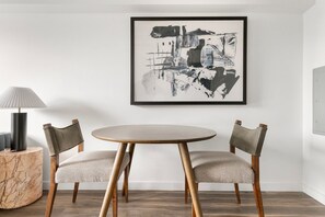 A dining area with a round table and two upholstered chairs, a marble side table, a modern lamp, and a framed abstract painting on the wall. - Blueground | Near North Side, rooftop, nr Riverwalk (Chicago)