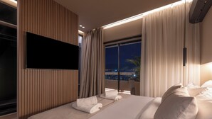 Ett modernt hotellrum med en stor säng, en platt-TV och utsikt över staden på natten.