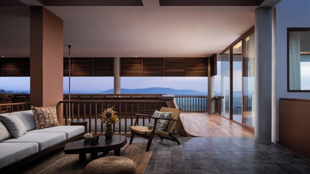 A modern living room with a sofa, a coffee table, and a chair, featuring a view of mountains through large windows. - Amaya Kampot (Kampot)