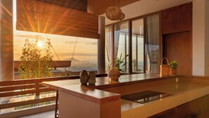 A modern kitchen with a large window, a wooden bench, and a view of the sunset. - Amaya Kampot (Kampot)