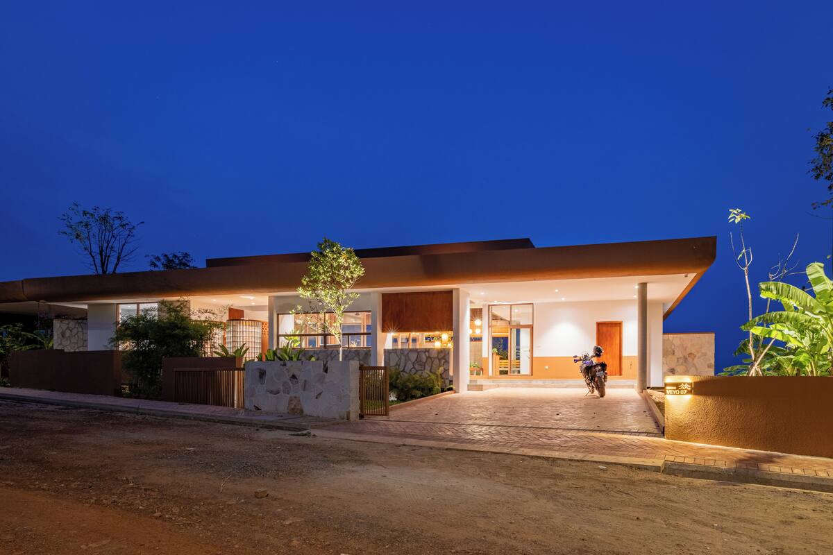 A modern house with a paved driveway, a motorcycle parked outside, and a well-lit entrance.