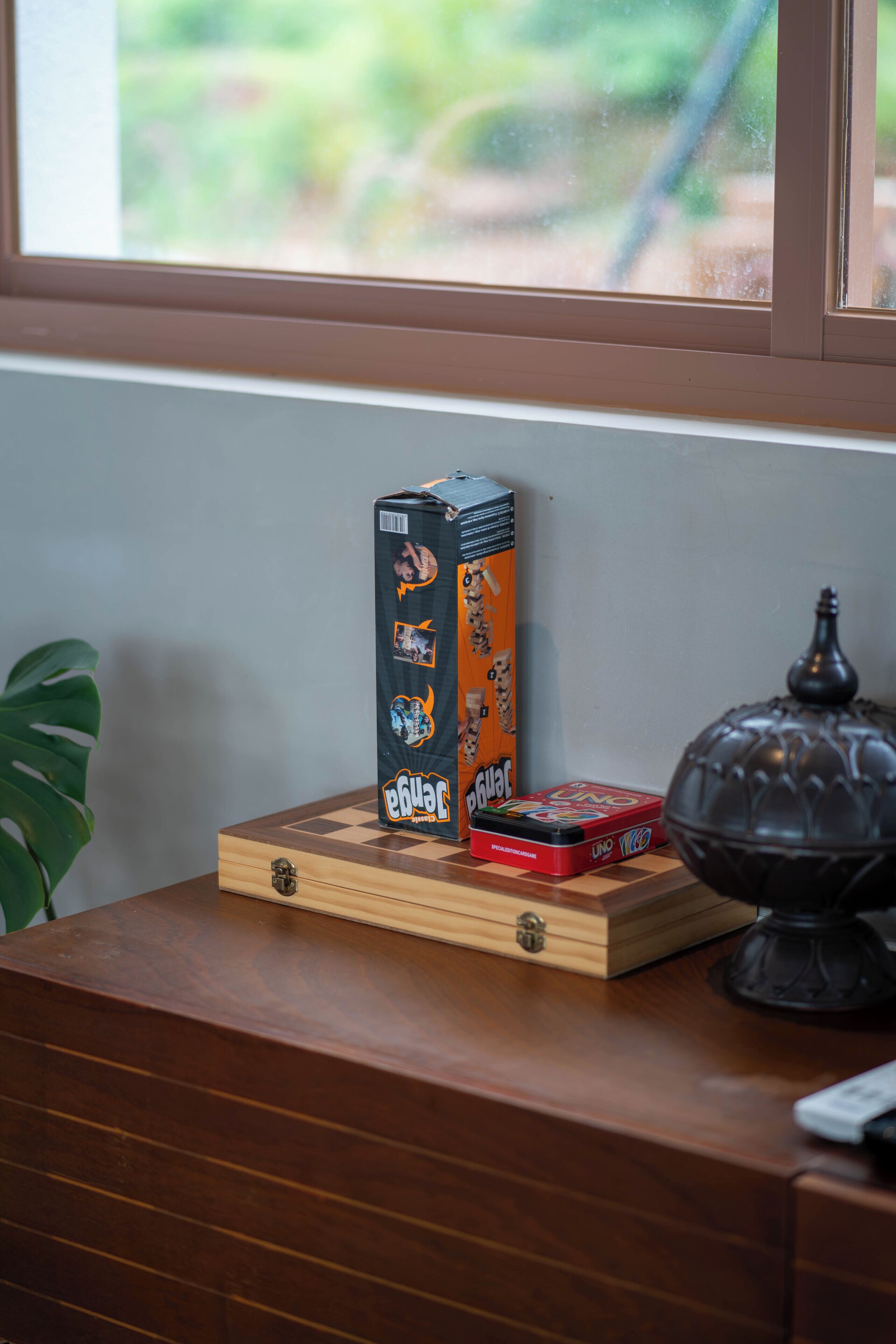 A wooden desk with a box of cigarettes, a lighter, and a decorative lamp.