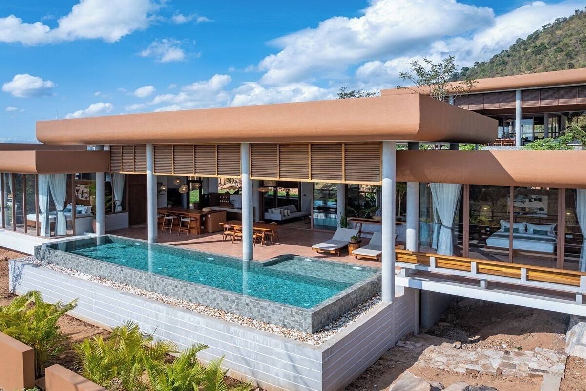 A modern villa with a swimming pool, outdoor seating, and large windows.