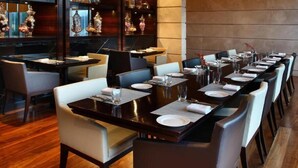 Un restaurant avec une longue table à manger, dressée pour accueillir plusieurs convives, et entourée de chaises.