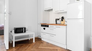 Una cucina compatta con mobili bianchi, un forno a microonde, un forno e un frigorifero.
