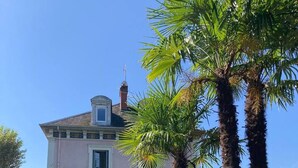 A two-story building with a pink facade, multiple windows, and a visible staircase leading to the entrance. - Appartement 76m² 2 chambres, parking et jardin (Aix-les-Bains)