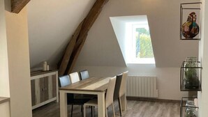 A dining area with a wooden table and chairs, a kitchen with cabinets, and a skylight. - Appartement 76m² 2 chambres, parking et jardin (Aix-les-Bains)
