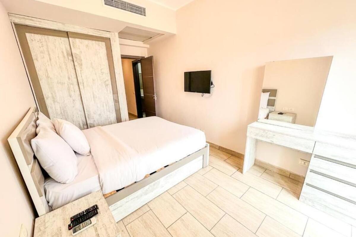 Une chambre à coucher comprenant un lit, une table de chevet, une télévision et un bureau avec un miroir.