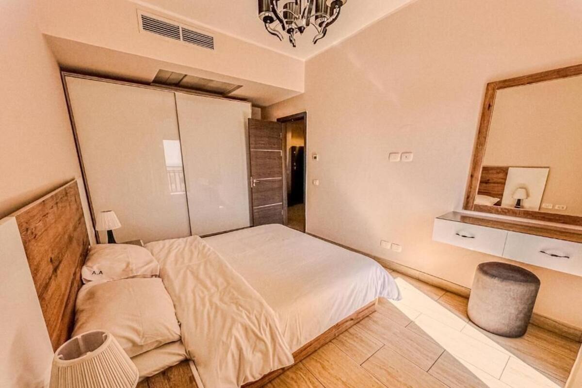 Une chambre à coucher comprenant un lit, une table de chevet, une lampe, une armoire et un miroir.