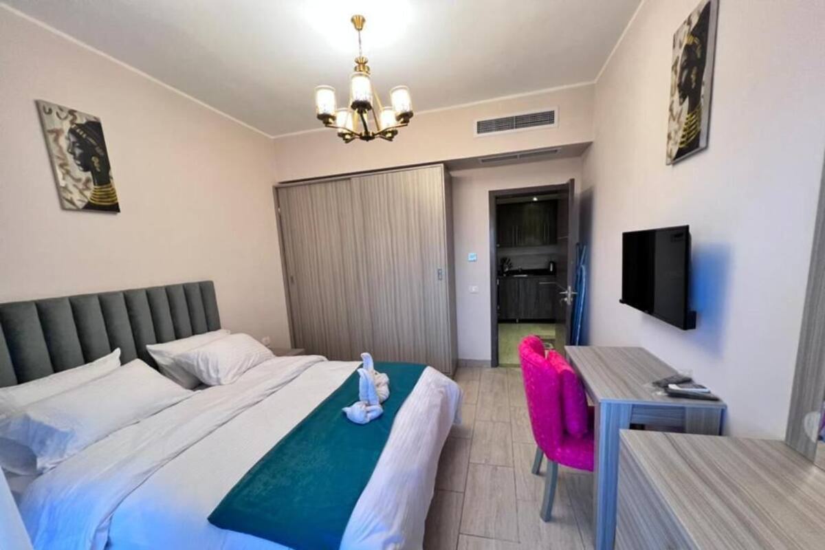 Une chambre d’hôtel équipée d’un lit, d’un bureau, d’une chaise, d’une télévision et décorée avec des œuvres d’art aux murs.