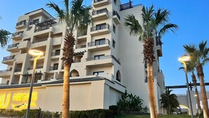 A multi-story hotel with balconies, palm trees, and a well-maintained lawn. - Al Dau Heights Apartments (Hurghada)