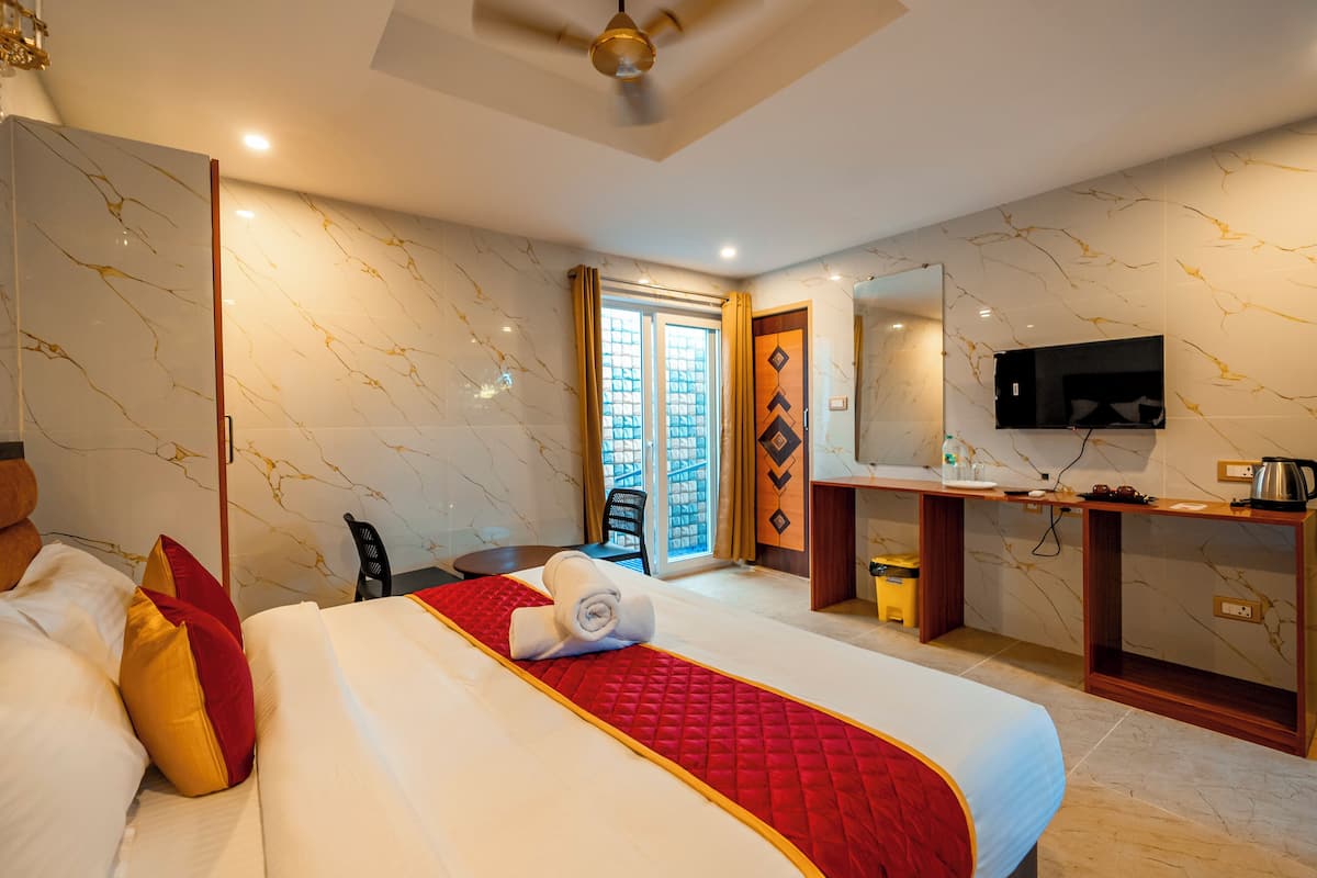 Una habitación de hotel con cama, escritorio, televisión y vistas al exterior.
