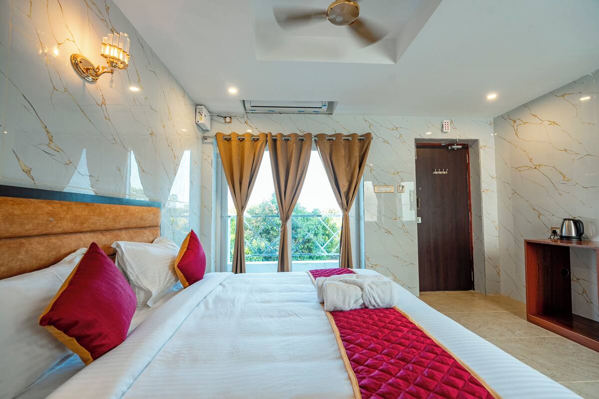 Una habitación de hotel con cama, cortinas, ventilador de techo, aire acondicionado y puerta.
