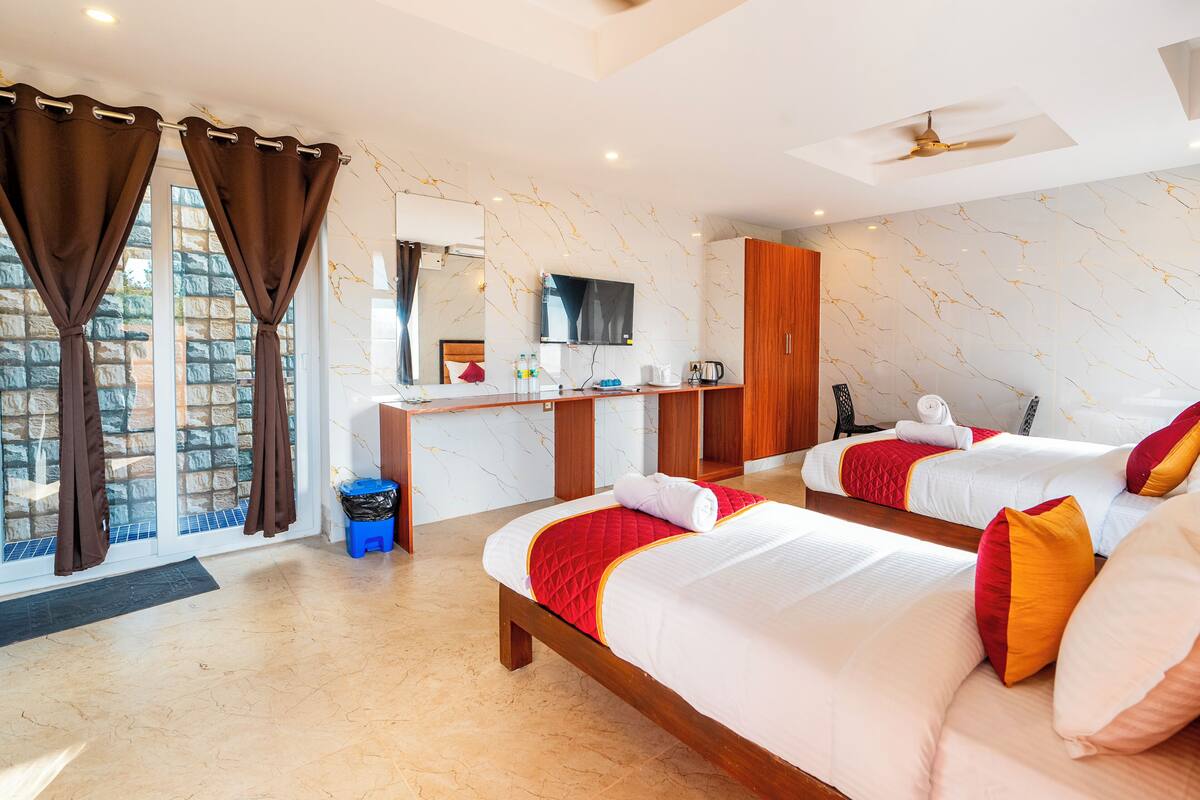 Habitación de hotel con dos camas, un escritorio, un televisor y vista a la ciudad.