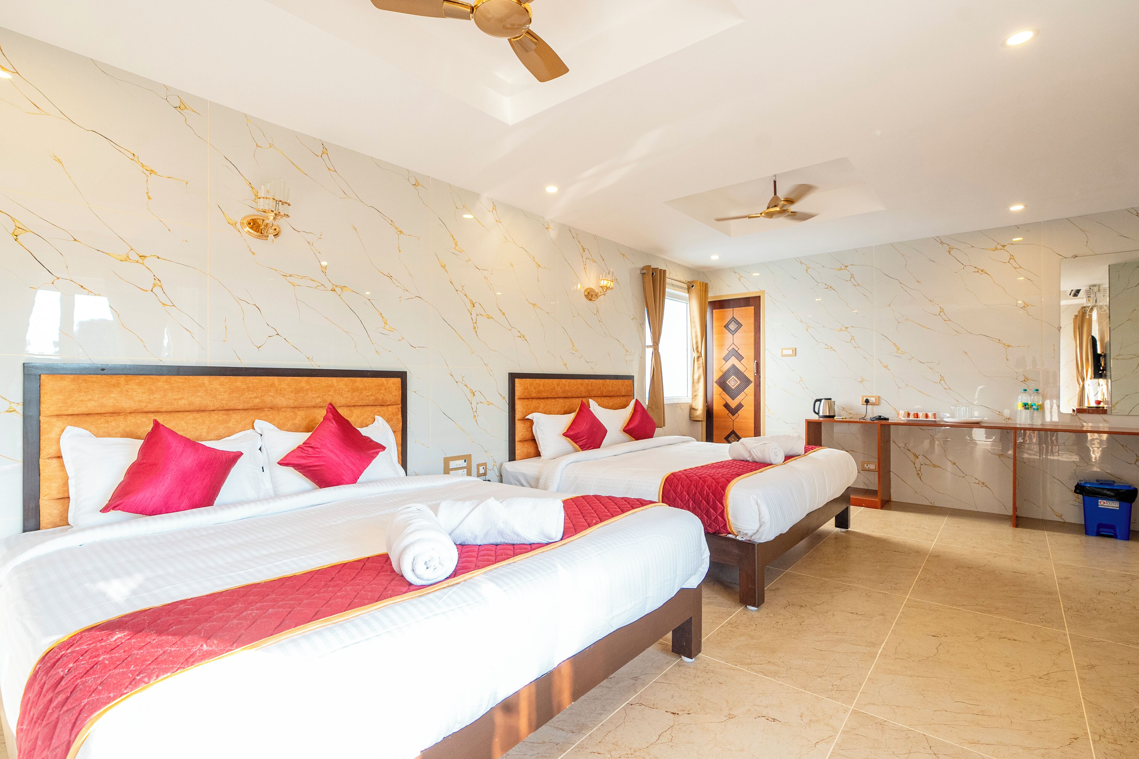 Une chambre d’hôtel avec deux lits, un ventilateur de plafond, une salle de bain avec un miroir et un mini-bar.