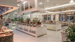 Un hall d’hôtel spacieux, doté d’un haut plafond, d’un espace buffet central et d’un coin salon avec des tables et des chaises.
