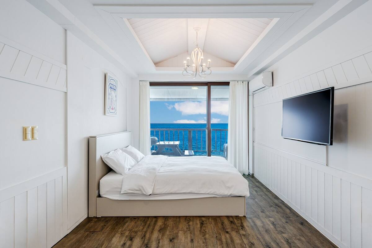 Une chambre avec un lit, une télévision et une vue sur la mer.