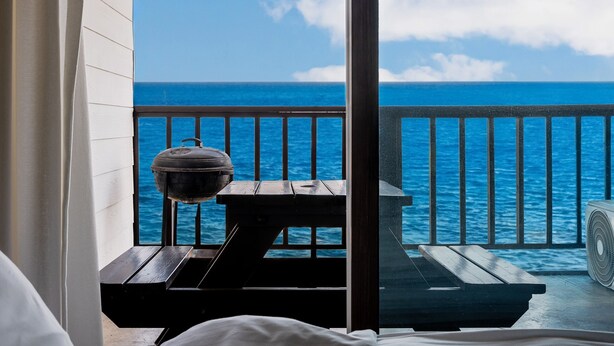 Ein Balkon mit Blick auf das Meer, einem Grill und einem Ventilator.